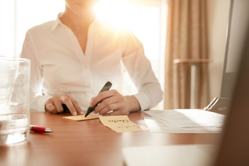 Woman writing on sticky notes at conference room